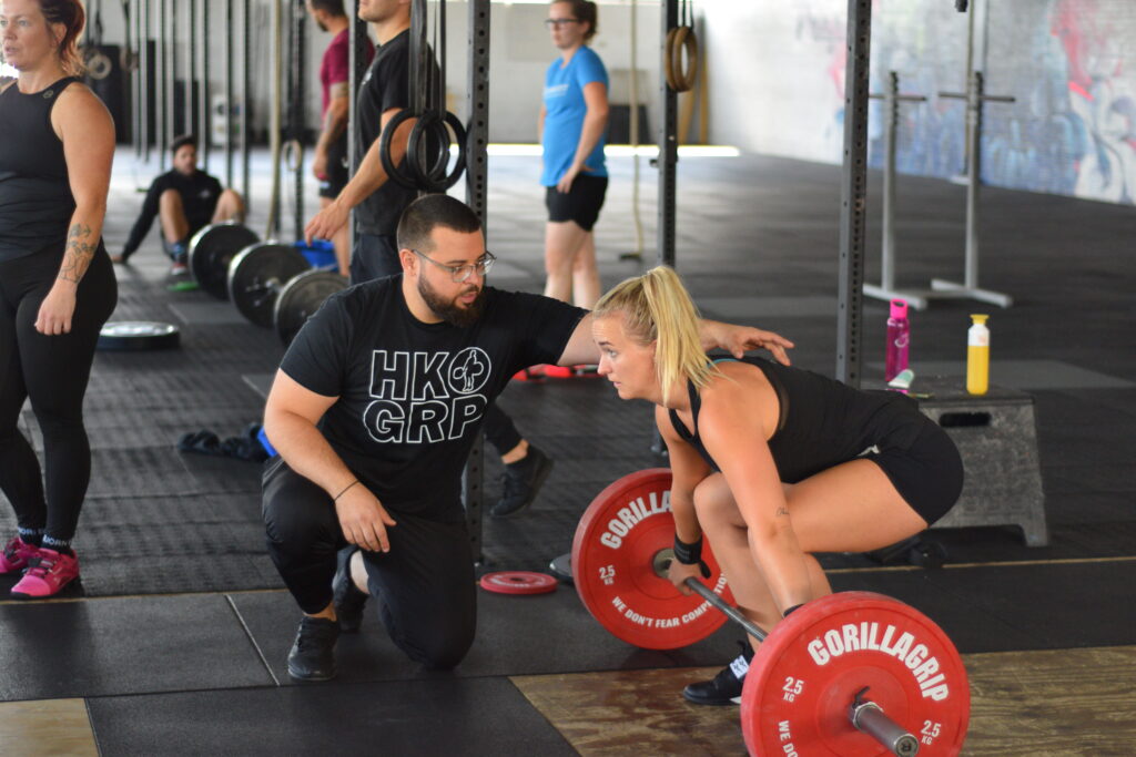 Trainer helpt met snatch oefening